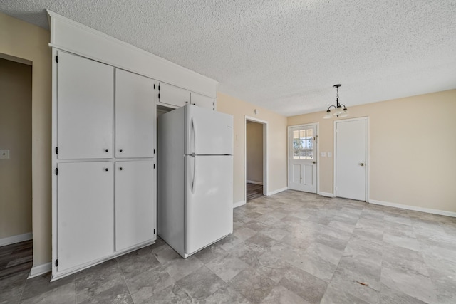 interior space with a textured ceiling, a closet, freestanding refrigerator, and baseboards