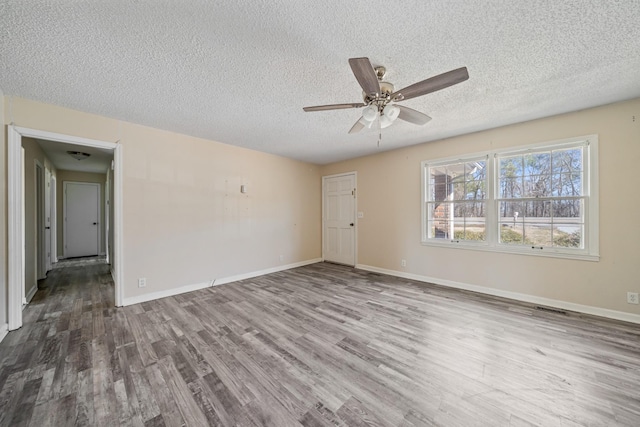 spare room featuring ceiling fan, a textured ceiling, baseboards, and wood finished floors