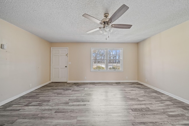 empty room featuring ceiling fan, a textured ceiling, wood finished floors, and baseboards