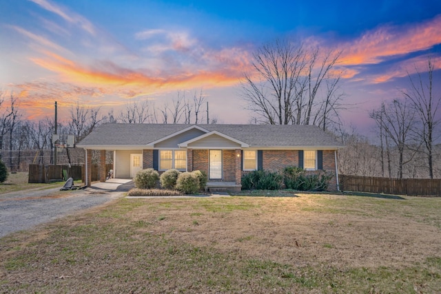 view of front of property with driveway, brick siding, a lawn, and fence