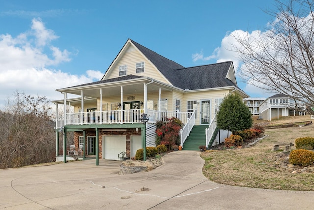 view of front of property featuring a shingled roof, covered porch, stairway, an attached garage, and driveway