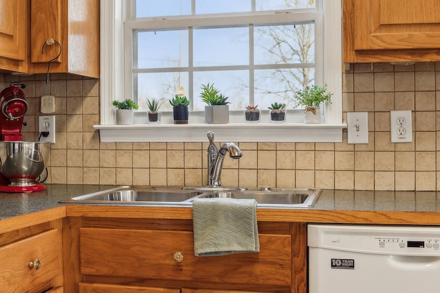 kitchen with white dishwasher, a sink, a wealth of natural light, and brown cabinets