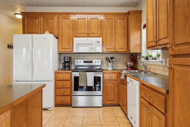 kitchen featuring white appliances, brown cabinets, and a sink