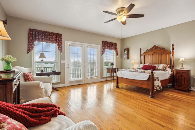 bedroom with access to exterior, multiple windows, light wood-style floors, and baseboards