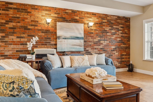 living room featuring brick wall, light tile patterned flooring, and baseboards