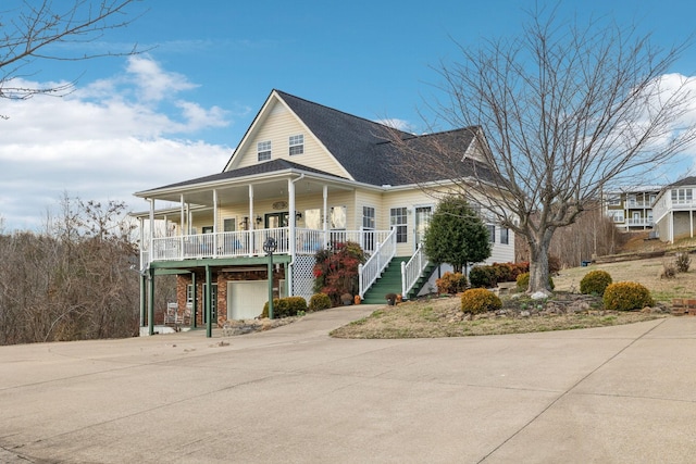 view of front facade featuring covered porch, stairway, and concrete driveway