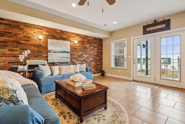 living area with light tile patterned floors, ceiling fan, recessed lighting, brick wall, and baseboards