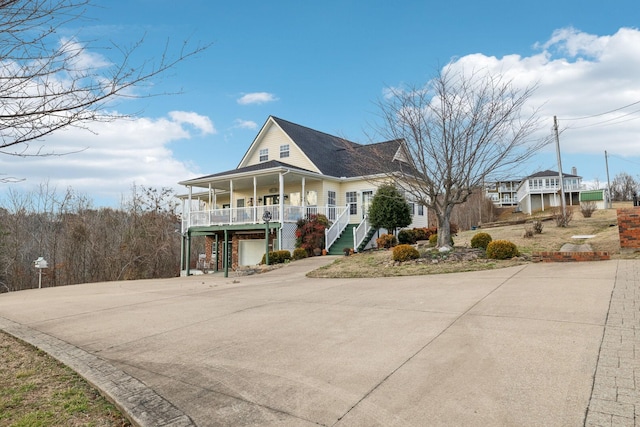 view of front of property with covered porch, stairs, and concrete driveway