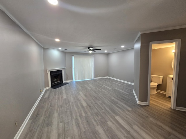 unfurnished living room with a fireplace with flush hearth, crown molding, baseboards, and wood finished floors