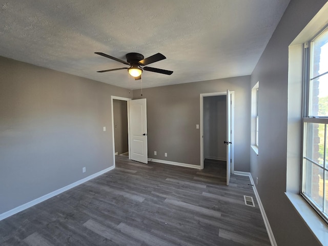 unfurnished bedroom with dark wood finished floors, a textured ceiling, baseboards, and ceiling fan