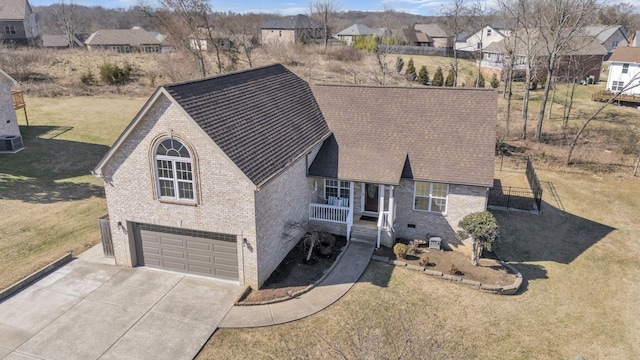 view of front of property with a garage, brick siding, concrete driveway, roof with shingles, and a front yard