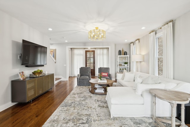 living area featuring an inviting chandelier, stairway, dark wood-type flooring, and recessed lighting