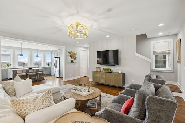 living area with recessed lighting, an inviting chandelier, baseboards, and wood finished floors