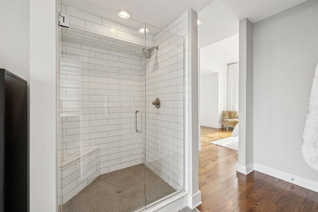 bathroom featuring baseboards, wood finished floors, and a shower stall