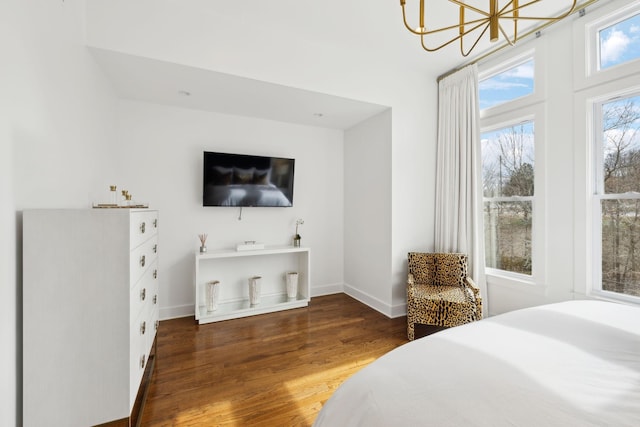 bedroom with a notable chandelier, baseboards, and wood finished floors