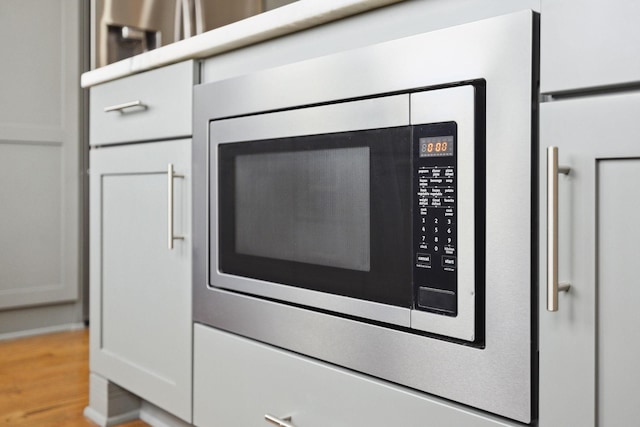 details featuring stainless steel microwave and wood finished floors