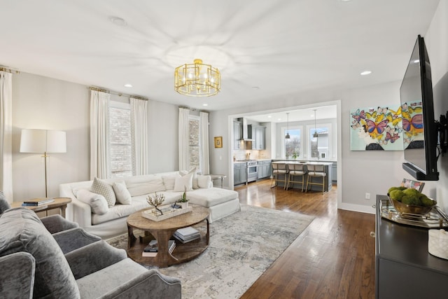 living area featuring dark wood-type flooring, recessed lighting, a notable chandelier, and baseboards