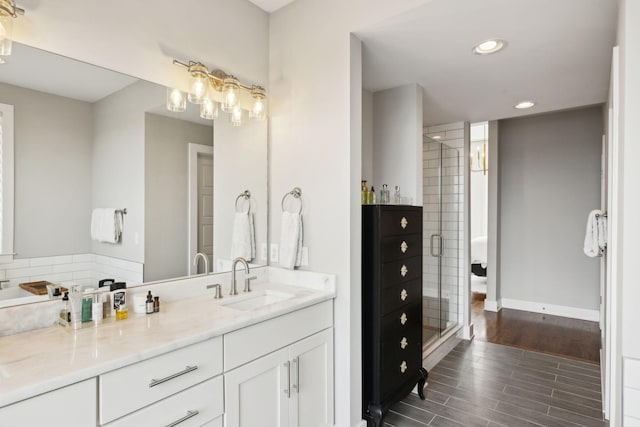 bathroom with recessed lighting, a shower stall, vanity, wood finished floors, and baseboards