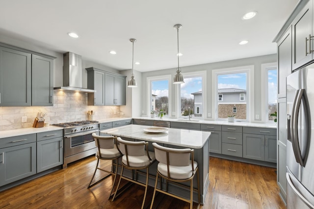 kitchen with tasteful backsplash, wall chimney exhaust hood, dark wood-type flooring, stainless steel appliances, and gray cabinetry