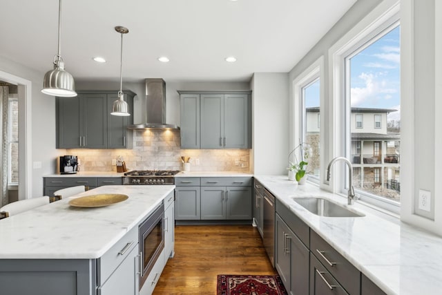 kitchen with wall chimney exhaust hood, appliances with stainless steel finishes, gray cabinets, and a sink