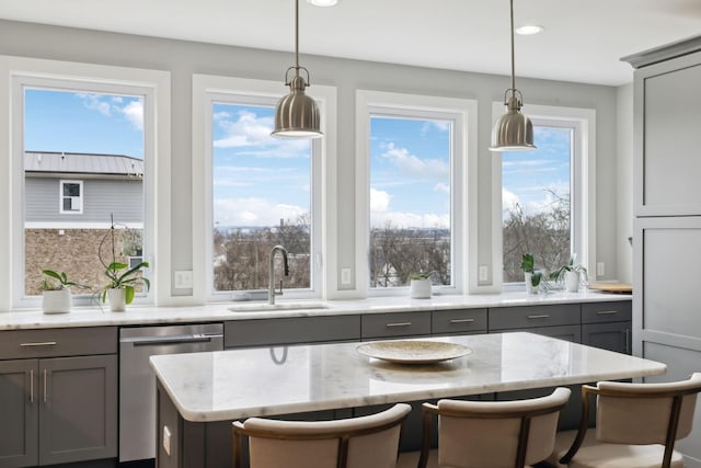 kitchen featuring light stone counters, gray cabinets, dishwasher, and a sink