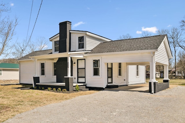 view of front facade with roof with shingles, a porch, a chimney, and driveway