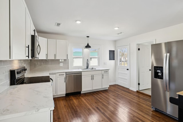 kitchen with backsplash, appliances with stainless steel finishes, dark wood-type flooring, white cabinets, and a sink