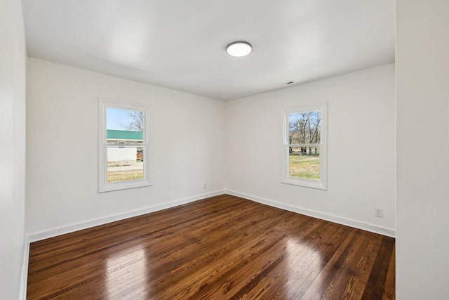 unfurnished room with visible vents, baseboards, and dark wood-type flooring