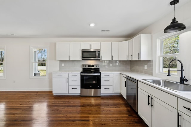 kitchen featuring tasteful backsplash, appliances with stainless steel finishes, dark wood-type flooring, and a sink