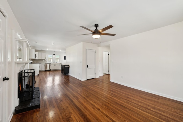 unfurnished living room featuring dark wood-style floors, baseboards, and a ceiling fan