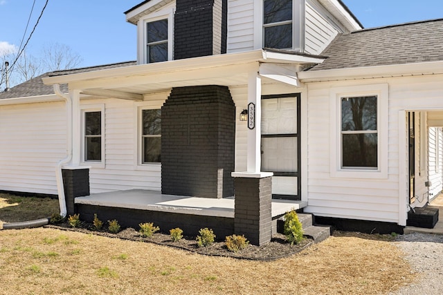 property entrance with covered porch and a shingled roof