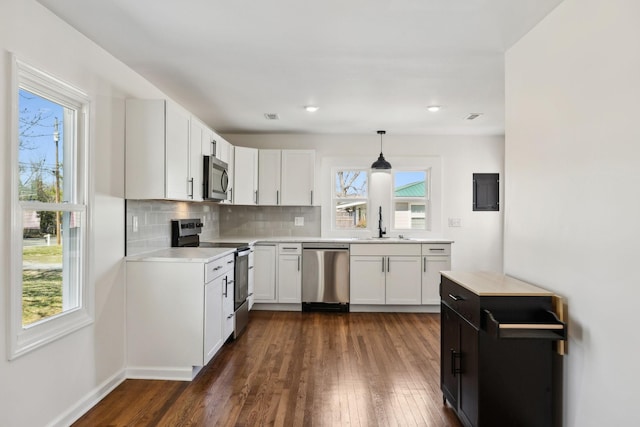 kitchen with decorative backsplash, appliances with stainless steel finishes, dark wood-style flooring, light countertops, and a sink