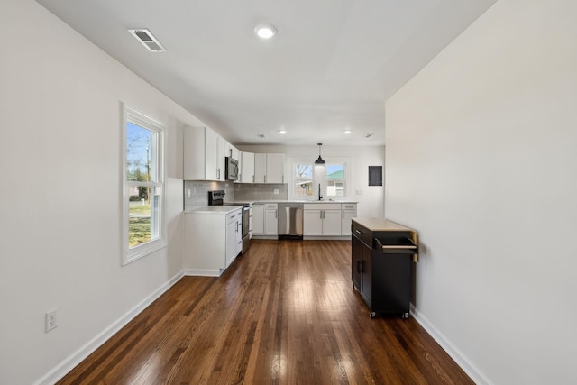 kitchen featuring white cabinets, decorative backsplash, dark wood-style flooring, stainless steel appliances, and light countertops