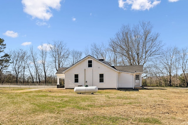 rear view of property featuring a yard and fence