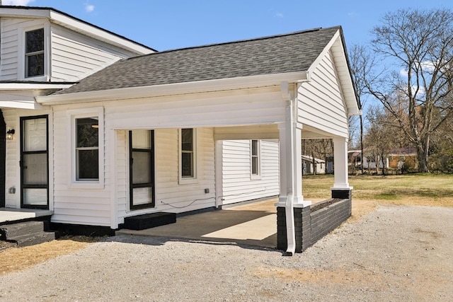 exterior space featuring a shingled roof, driveway, and a carport