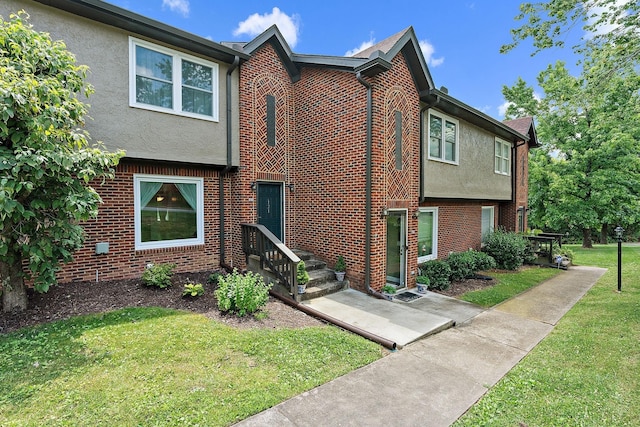 multi unit property featuring brick siding, a front yard, and stucco siding