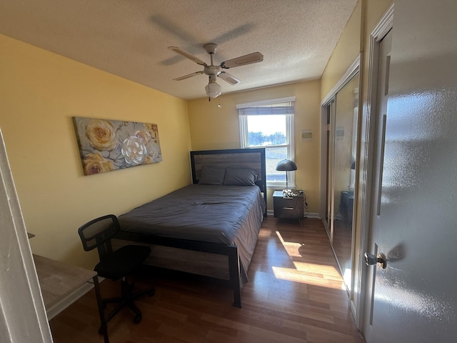 bedroom with ceiling fan, a textured ceiling, baseboards, and wood finished floors