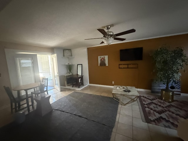 living area featuring ceiling fan, ornamental molding, tile patterned flooring, and baseboards