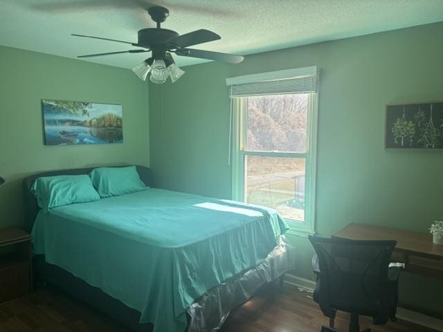 bedroom featuring a textured ceiling, ceiling fan, multiple windows, and wood finished floors