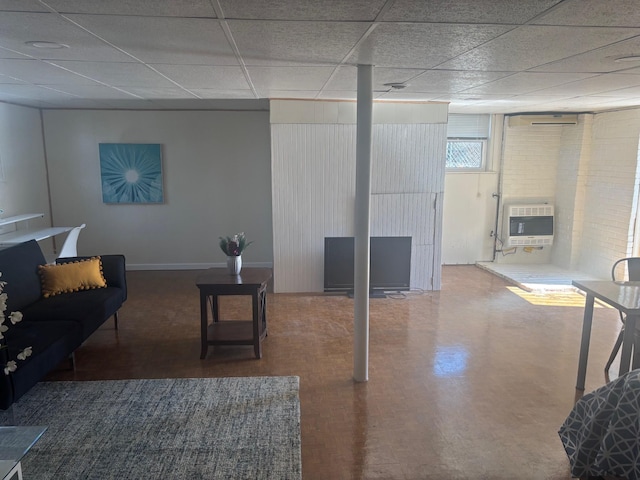 below grade area featuring a paneled ceiling, baseboards, and heating unit