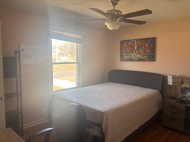 bedroom with dark wood finished floors, a textured ceiling, and ceiling fan