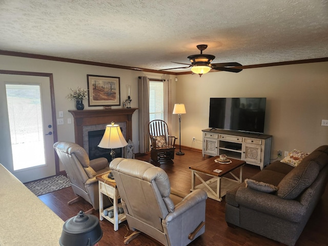 living room with plenty of natural light, ornamental molding, wood finished floors, and a tile fireplace