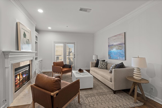 living area with wood finished floors, a tile fireplace, visible vents, and crown molding