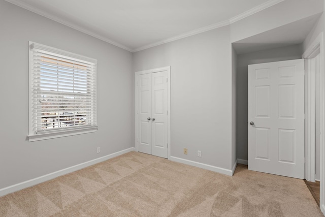 unfurnished bedroom with ornamental molding, a closet, carpet, and baseboards