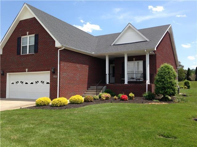 view of front of property featuring brick siding, a porch, concrete driveway, an attached garage, and a front lawn