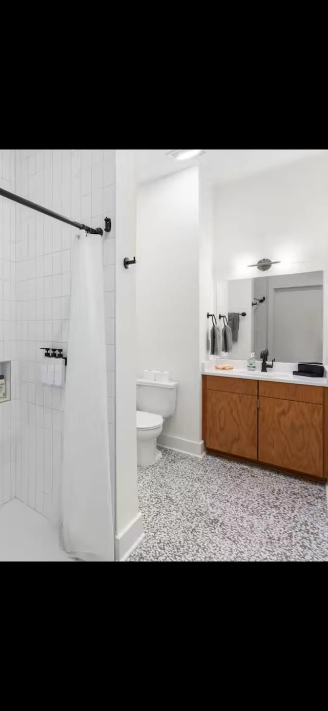 full bath featuring curtained shower, baseboards, vanity, and toilet