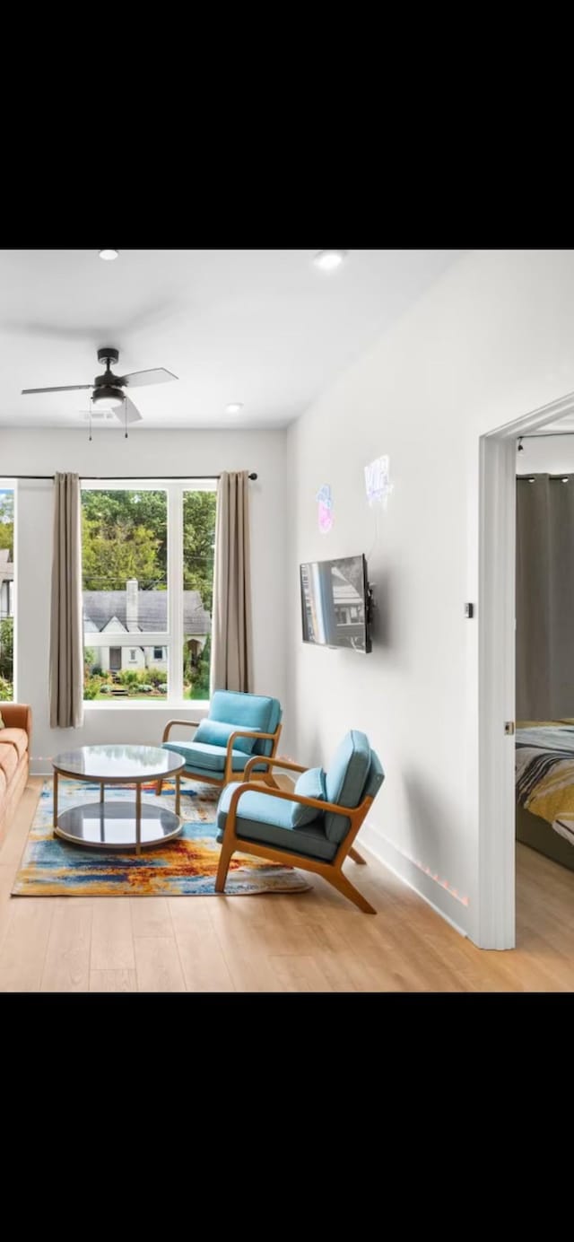 living room featuring ceiling fan, plenty of natural light, baseboards, and wood finished floors