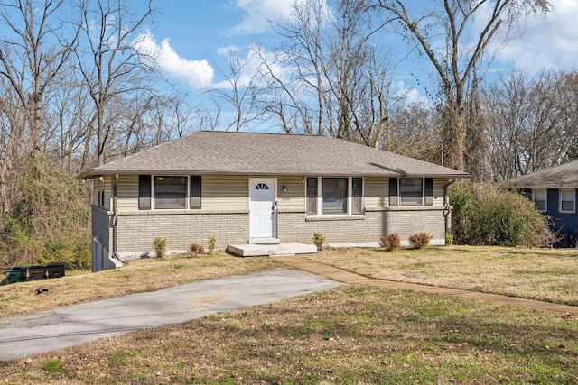 view of front facade with a front yard, brick siding, and roof with shingles