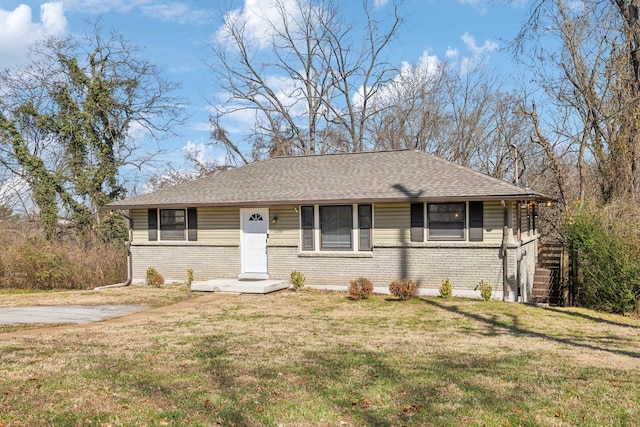 view of front of house with brick siding, roof with shingles, and a front yard