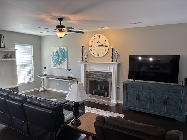 living area with baseboards, visible vents, ceiling fan, dark wood-type flooring, and a high end fireplace